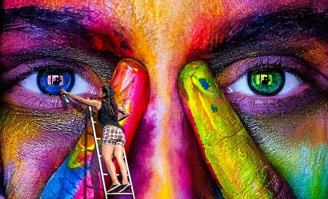 A girl painting a face on the dec using multiple colors